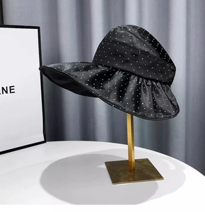 Detail of wide brim sun hat in black with white polka dots and elegant pleated texture