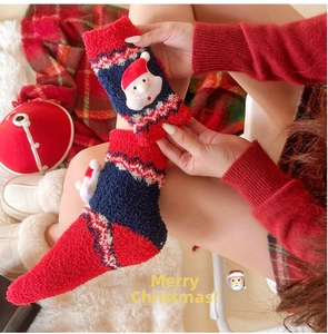 Gros plan de chaussettes de Noël duveteuses avec broderie Père Noël en polaire corail