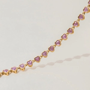 Macro detail of gold-plated chain bracelet with heart-shaped pink zircon gemstones