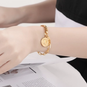 Détail du bracelet pièce en or avec profil Elizabeth II et fermoir OT sur le poignet