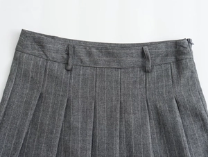 Détail d'une jupe plissée grise à rayures avec taille haute et passants de ceinture