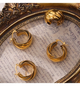 Close-up of golden chunky twisted earrings on vintage parchment with metallic frame
