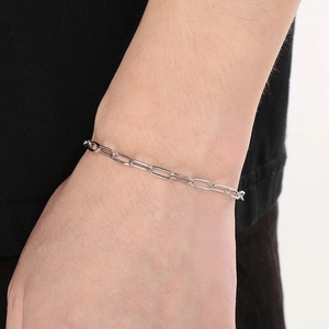 Close-up of silver stainless steel oval link chain bracelet on a model's wrist