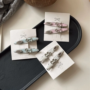 Three pairs of dog-shaped hair clips with egg rhinestones on a stylish black tray