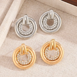 Macro detail of gold and silver interlocking hoop earrings with sparkling pave rhinestones