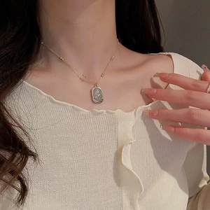 Close-up of golden stainless steel necklace featuring a rectangle rose relief pendant