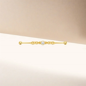 Close-up of golden industrial barbell earring with clear zircon and chain detail