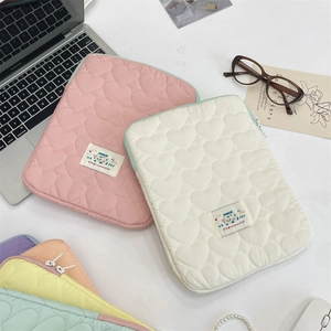 Detalle del patrón de corazón acolchado y etiqueta Happy en la funda de laptop macaron