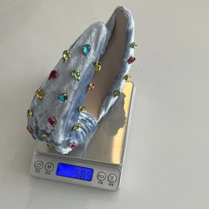 Macro del cerchietto in velluto azzurro da 58,5 g con strass colorati su una bilancia digitale