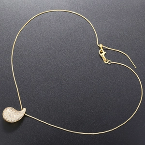 Detail of gold teardrop pendant with micro-paved zircons on a delicate chain necklace