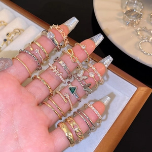 Close-up of stacked gold and silver pearl rings with butterfly and heart charms