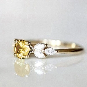 Macro shot of gold ring featuring a yellow center stone and marquise diamond leaves
