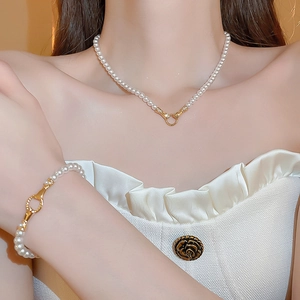 Detail of elegant gold-plated pearl necklace and bracelet set on a model