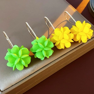 Dettaglio orecchini a fiore in acrilico verde fluo e giallo con ganci in diamanti sintetici