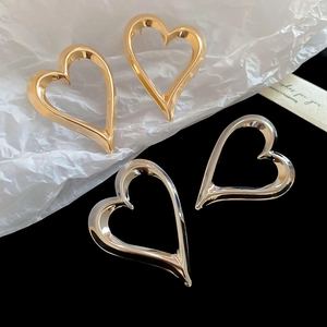 Close-up of gold and silver chunky heart-shaped earrings with a polished metallic finish