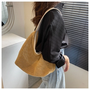 Fashionable straw shoulder bag shown on model with light blue jeans and black top