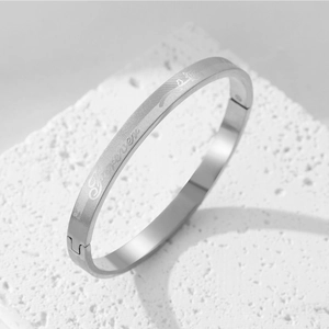Minimalist silver titanium steel bangle with fovelove grid pattern on white stone
