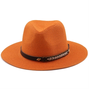 Detail of vibrant orange straw hat featuring a brown leather band and metal rivet accents