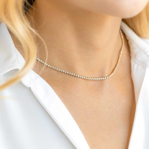 Close-up of elegant gold tennis necklace with sparkling crystals on a model neck