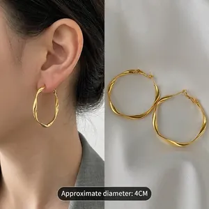 Professional view of 4CM gold twisted geometric hoop earrings on a model and silk fabric