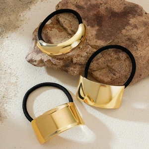 Three gold metal hair cuffs with elastic bands on a natural stone background