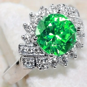 Vista macro di un anello di lusso con una grande pietra verde e un alone di diamanti