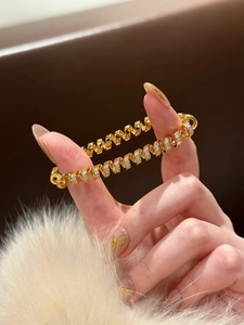 Macro detail of 18K gold-plated spiral bracelet with sparkling white cubic zirconia stones