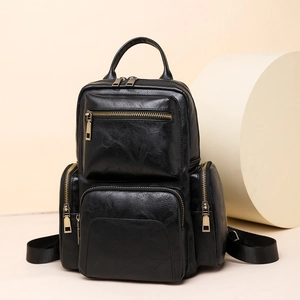 Detailed close-up of a black PU leather backpack with vintage gold metal zippers and pockets