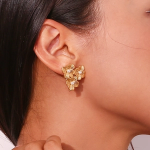 Detailed view of triple gold flower earrings with pearls worn by a fashion model