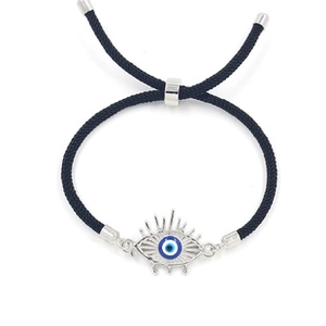 Macro view of woven black leather bracelet featuring a blue devil eye charm