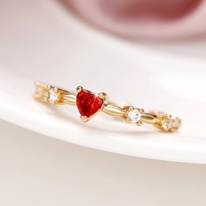 Macro shot of heart-shaped red zircon ring with gold band and sparkling diamonds