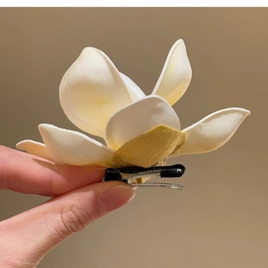 Detail view of a white frangipani fabric flower hair clip with yellow velvet center