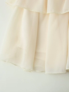 Dettaglio ravvicinato delle balze in chiffon crema con elegante trama a pieghe