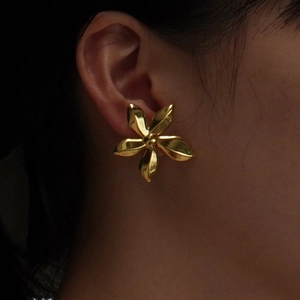 Fashionable gold five-petal flower stud earrings shown on a model with metallic luster