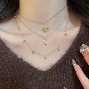 Three-layer gold star and moon pendant necklace set on female model in knitwear