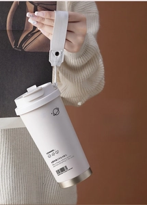 Close-up of cream white insulated coffee mug with woven carry strap and planet logo