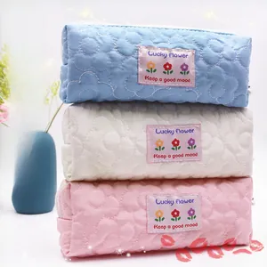 Detailed stack of quilted floral pencil cases in blue, beige, and pink fabric
