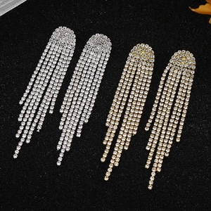 Detail of long rhinestone tassel earrings in gold and silver finish on black background