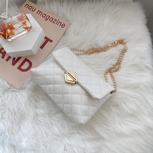 White quilted chain shoulder bag with gold geometric lock on white plush background