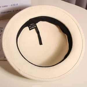 Detail of cream wool hat interior showing 100% wool label and adjustable ribbon