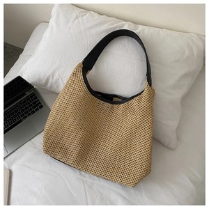 Detailed texture of beige woven straw tote bag with black strap on cozy white bedding