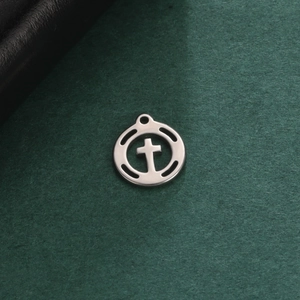 Macro shot of silver hollow circular pendant with a cross design on dark felt background