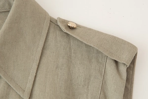 Detail shot of khaki linen dress shoulder tab with a gold geometric faceted button