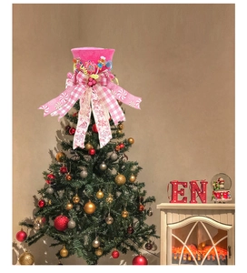 Close-up of pink gingerbread man top hat tree topper with candy and large plaid bow