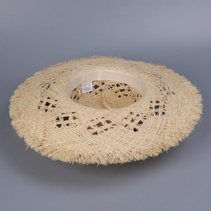 Detailed close-up of hollow-out woven raffia sun hat with raw fringe edges and inner label