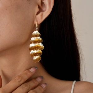 Detailed view of layered gold ginkgo leaf tassel earrings worn by a model