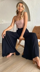 Détail du haut rose à fines bretelles associé à un pantalon noir large à taille haute
