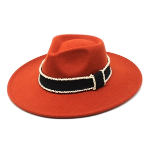 Detail of orange wool fedora featuring black ribbon with pearl trim and wide brim