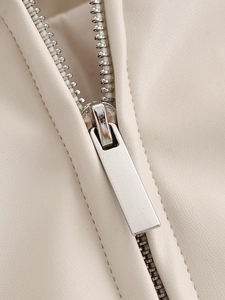 Macro detail of silver metal zipper and stitching on beige faux leather jacket