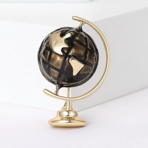 Detail of a gold globe brooch with black enamel inlay and intricate metallic map lines